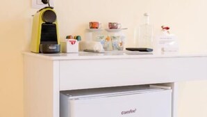 A compact kitchenette with a coffee machine, a small refrigerator, and a flat-screen TV mounted above the counter. - GLAM PARMA (Parma)