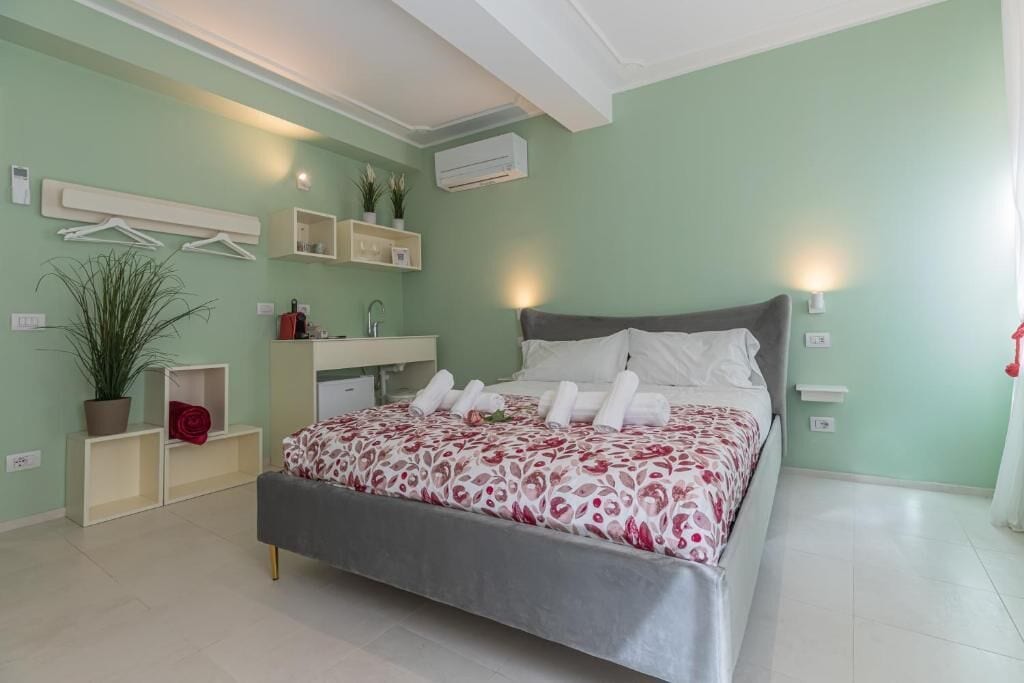 A bedroom with a bed, bedside tables, a wardrobe, a potted plant, and a window.