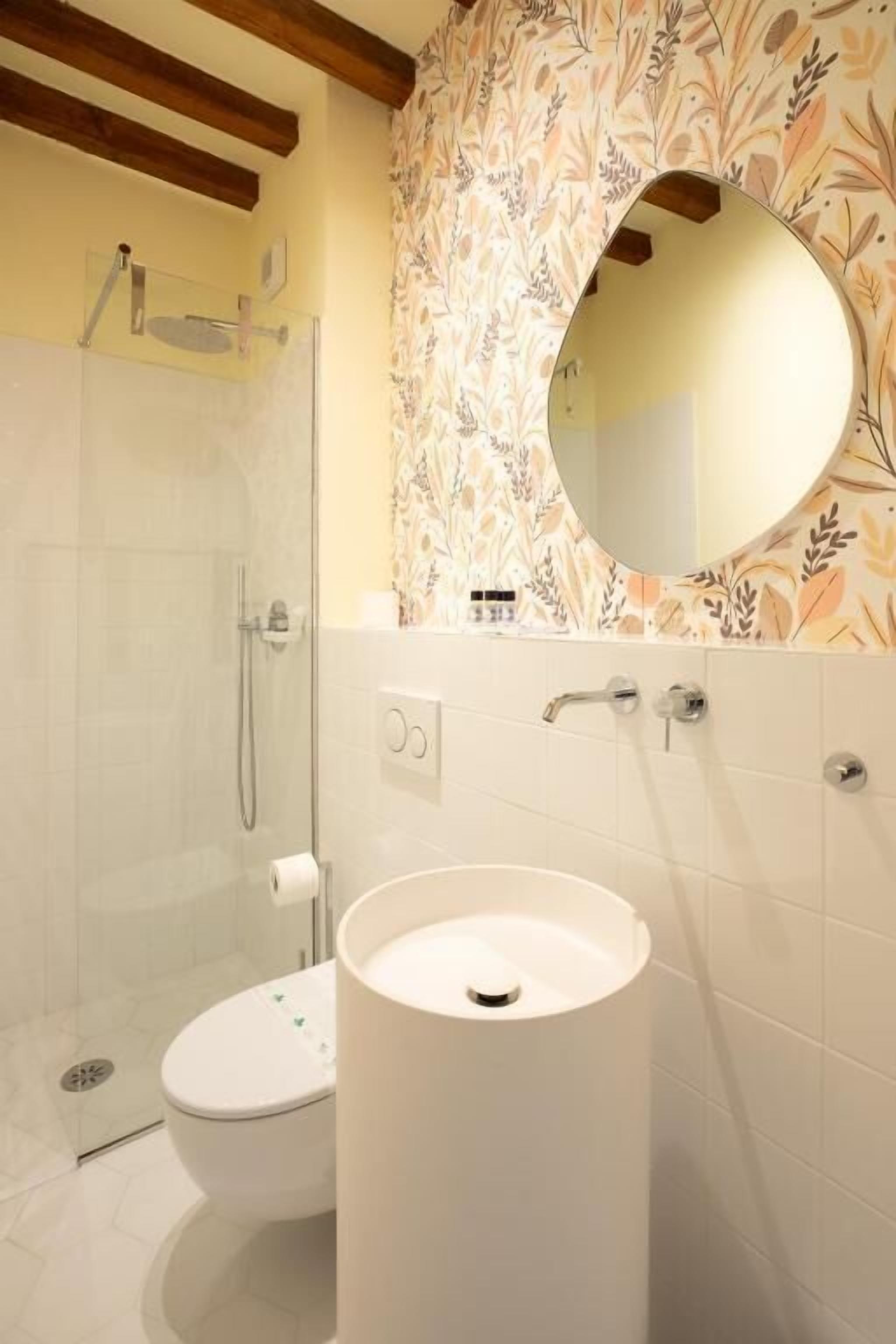 Une salle de bain équipée de toilettes, d’un lavabo, d’une douche et d’un miroir.