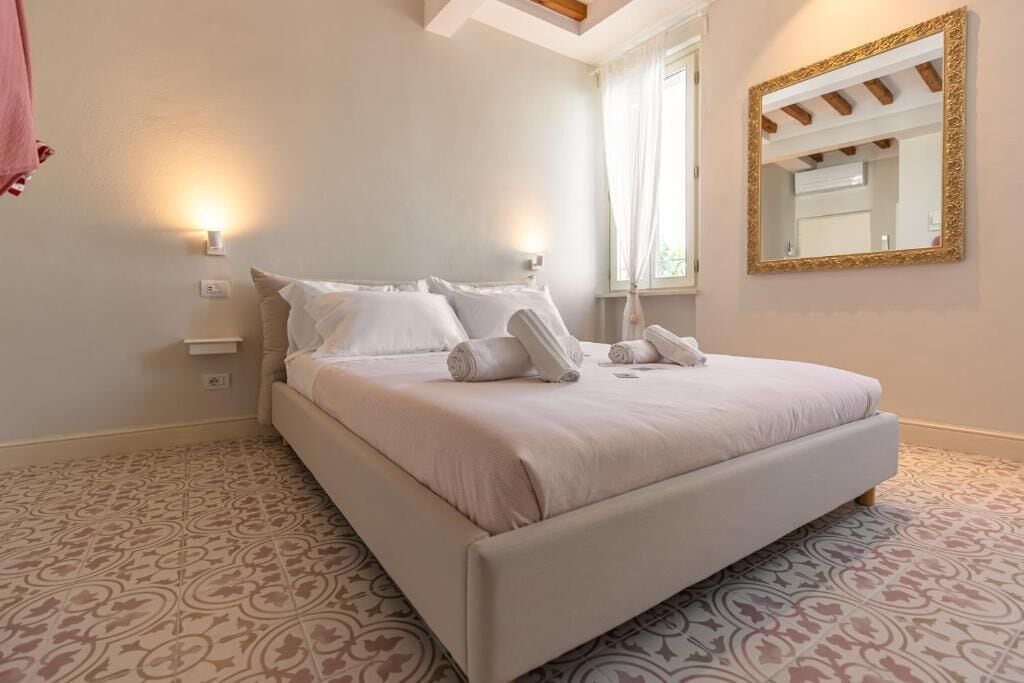 A bedroom with a bed, two bedside lamps, a large mirror, and patterned carpet.