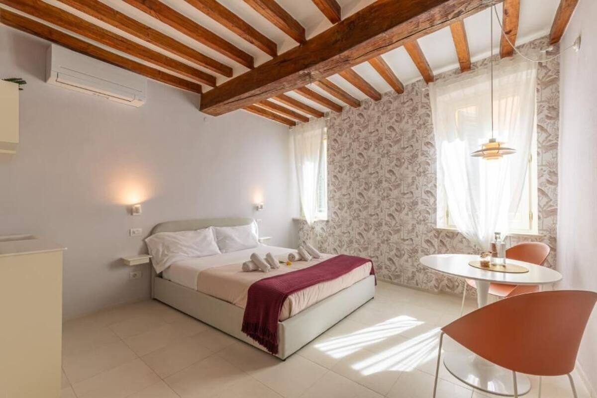 A bedroom with a bed, bedside table, and a small round table with a chair.