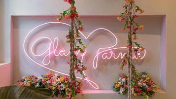 Eine Neonreklame mit dem Schriftzug 'Glory Parade' in Herzform, umgeben von Blumenarrangements.