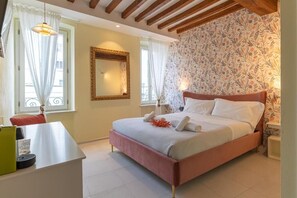 A bedroom with a bed, a bedside table, a mirror, and a window with curtains. - GLAM PARMA (Parma)