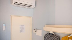 A room with a door, an air conditioning unit, a wall-mounted light switch, and a clothing rack with a patterned shirt. - GLAM PARMA (Parma)