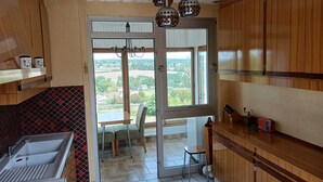 A kitchen with a sink, a dining area with a table and chairs, and a view through a glass door. - Charming gîte with panoramic views over the hills of the Morvan (James)