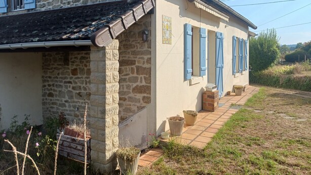 A stone house with blue shutters, a tiled patio, and a garden area. - Charming gîte with panoramic views over the hills of the Morvan (James)