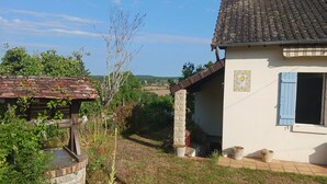 A rustic house with a tiled roof, a stone pillar, and a small garden area. - Charming gîte with panoramic views over the hills of the Morvan (James)