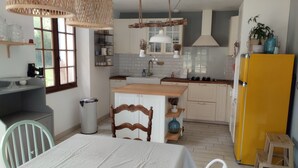Een keuken met witte kastjes, een gele koelkast en een eethoek met een tafel en stoelen.