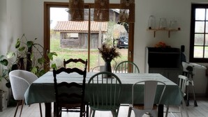 Een eetgedeelte met een tafel, stoelen, hangende lampen en uitzicht op buiten.