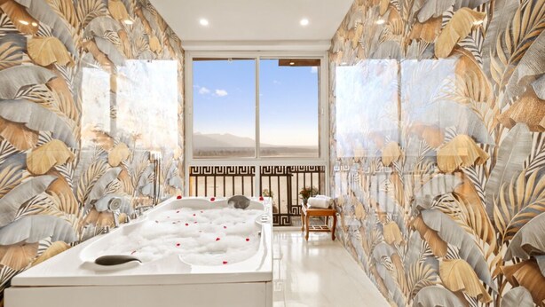 A spa room with a hot tub, a view of the mountains, and a decorative wall with leaf patterns. - The Neeraj Ganga Rani Mahal (Rishikesh)