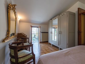 Un dormitorio con cama, una silla de madera, un armario grande y un espejo.