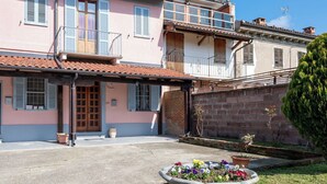 Ein zweistöckiges Gebäude mit Balkon, Blumenbeet im Vordergrund und einer Ziegelwand.