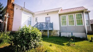 Ein zweistöckiges Haus mit einem Ziegelkamin, einer Veranda und einem kleinen Garten.