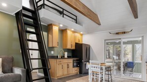 A modern kitchen with wooden cabinets, a stainless steel refrigerator, and a dining area with a table and chairs.