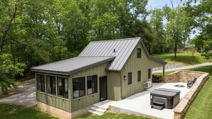 A house with a covered patio, a stone wall, and a metal roof.