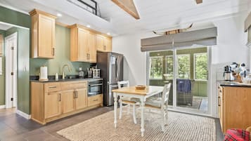 Een moderne keuken met houten kastjes, een roestvrijstalen koelkast en een eethoek met een tafel en stoelen.
