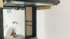 A kitchen with a black range hood, a wooden cabinet above, and a black countertop. - Radama Hotel & Studios (Antananarivo)