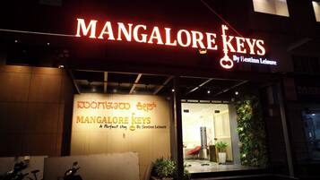 A hotel entrance with signage for 'Mangalore Keys' and a sign in a local language.