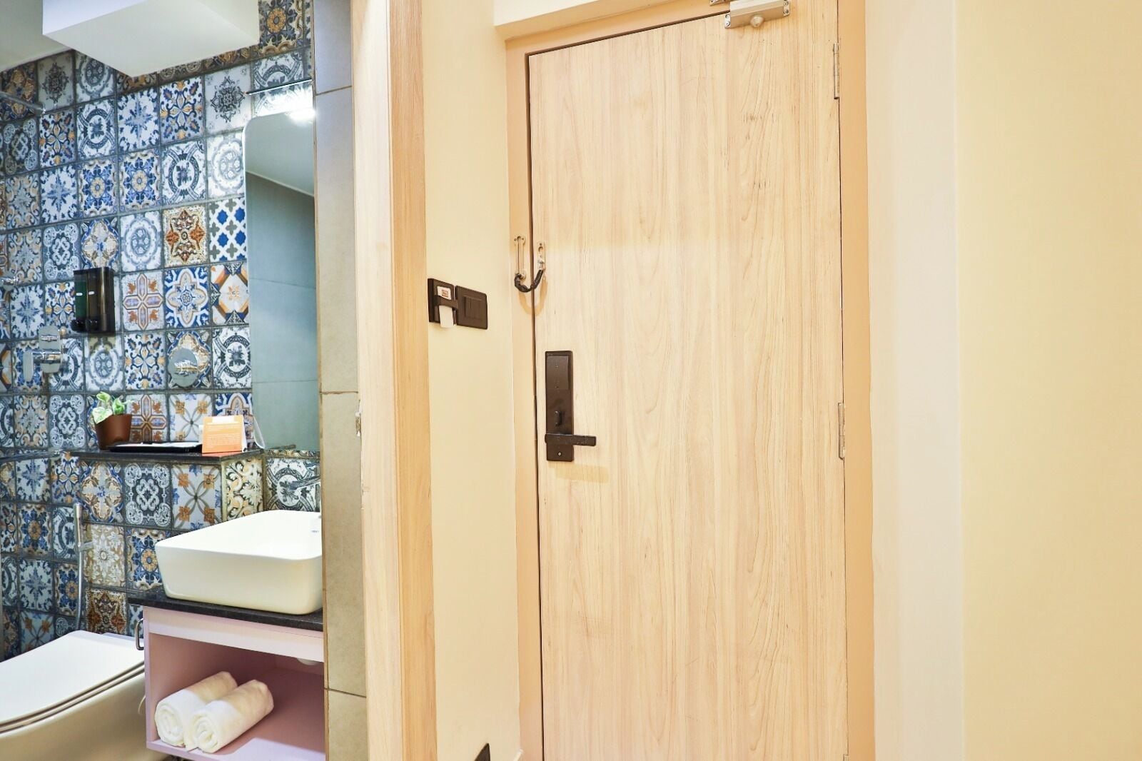 A bathroom with a sink, a toilet, a wooden door, and a tiled wall.