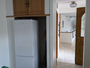 Eine Küche mit einem weißen Kühlschrank, Holzschränken und einem gefliesten Boden.