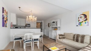 Un soggiorno moderno con zona pranzo, un lampadario, un divano e un tavolino da caffè.