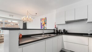 Una cucina moderna con isola centrale, elettrodomestici in acciaio inossidabile e un lampadario.