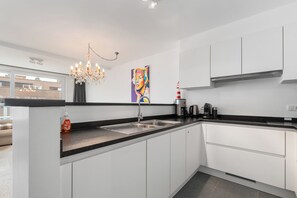 A modern kitchen with a central island, stainless steel appliances, and a chandelier. - Dukdalf 20 0403 + G-2/17 (Nieuwpoort)