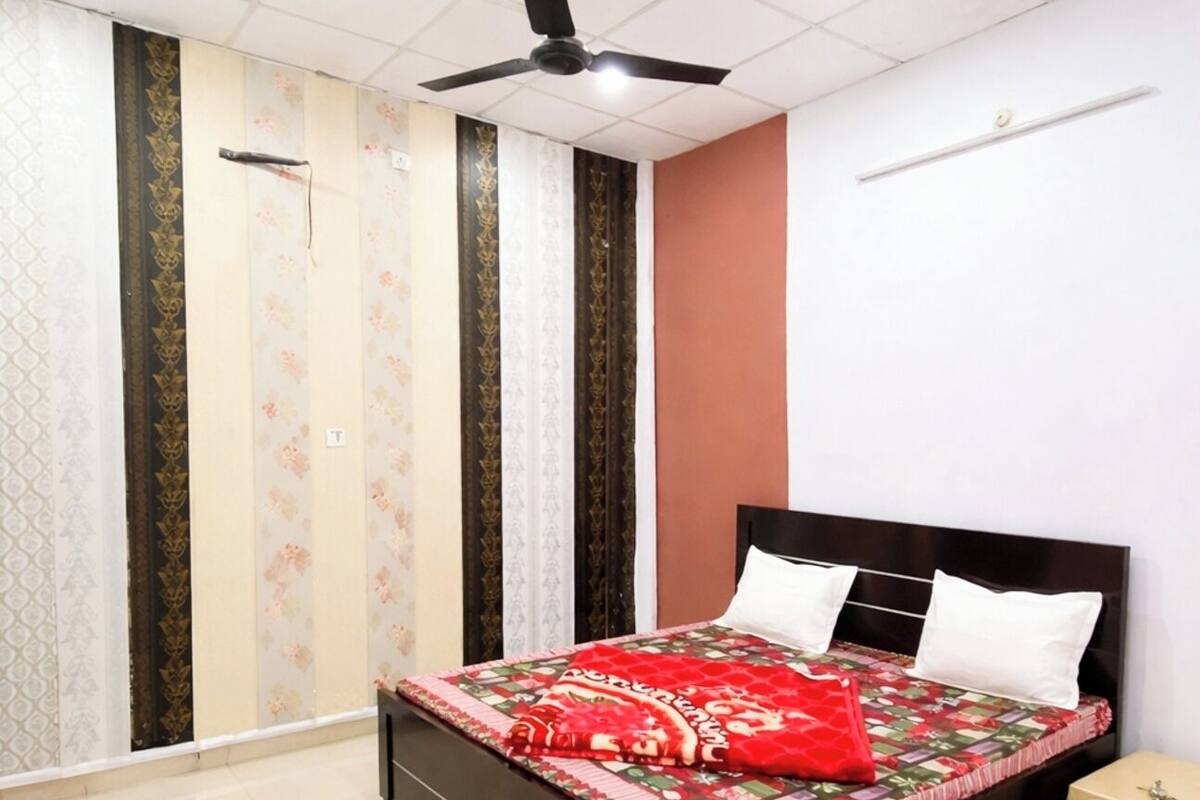 A bedroom with a bed, a ceiling fan, a nightstand, and a window with curtains.