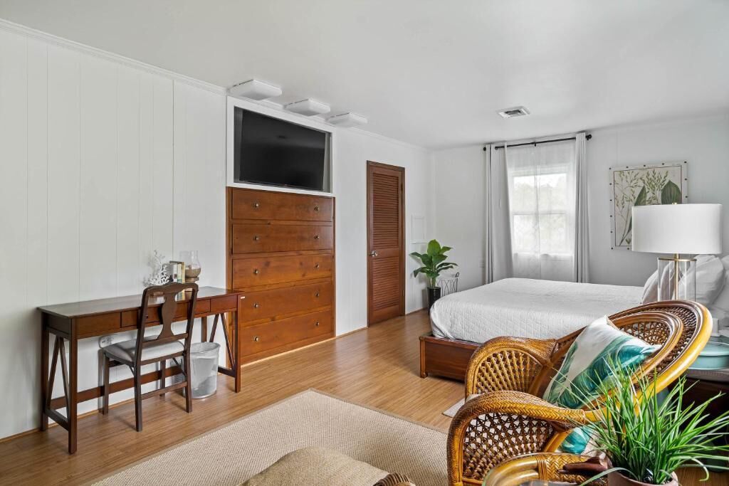Un dormitorio con un aparador de madera, una cama, un escritorio y una silla.