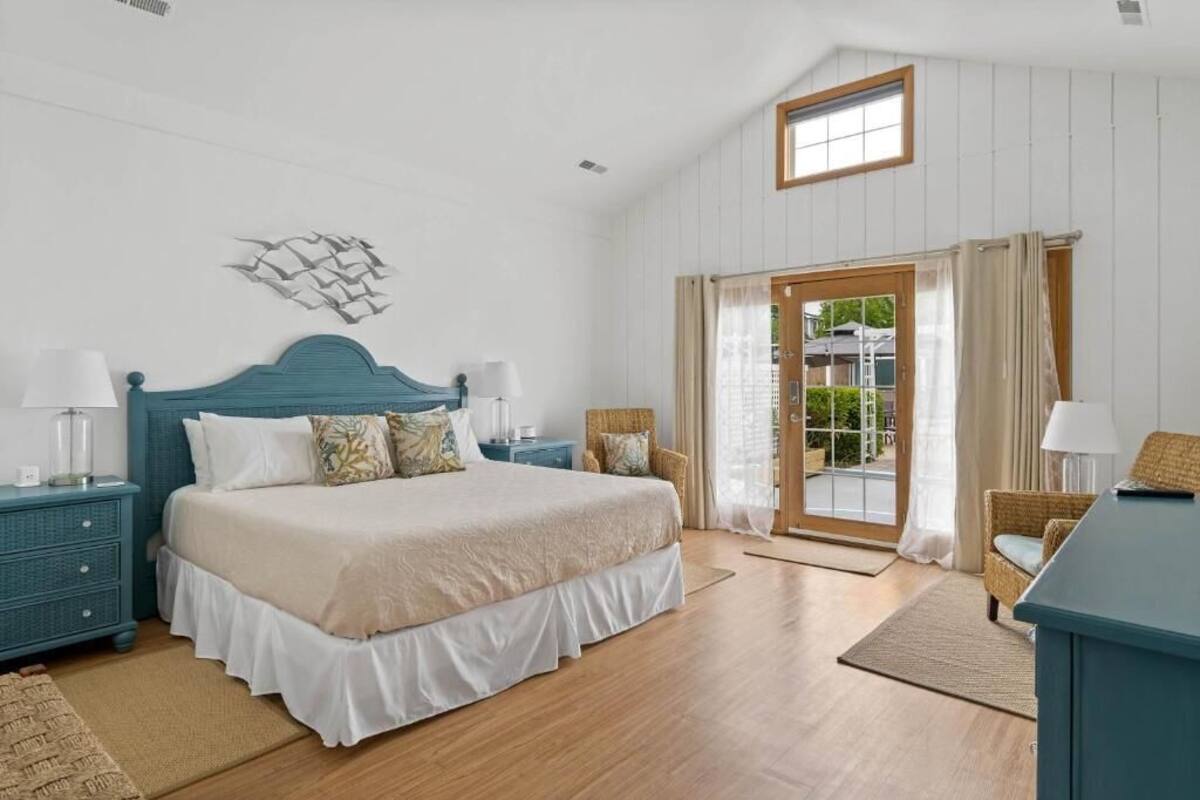 A bedroom with a bed, nightstands, a chair, a window, and a door.