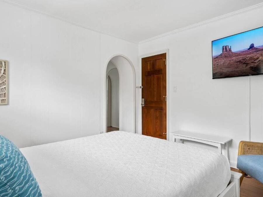 Ein Schlafzimmer mit einem Bett, einem Fernseher, einer Tür und einem Wandbild.