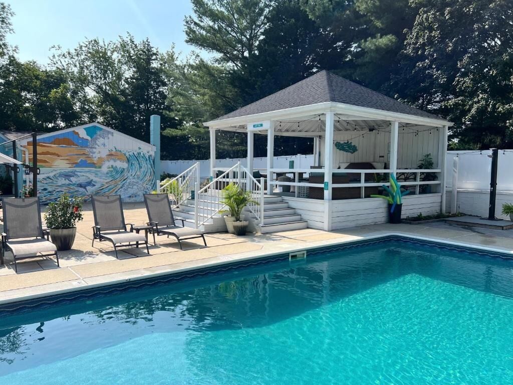 Une piscine avec des chaises longues et un kiosque.