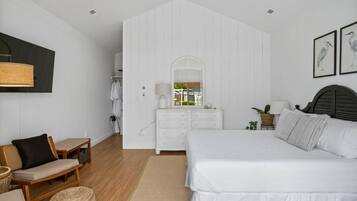 Une chambre à coucher comprenant un lit, une commode, une chaise, un miroir et une lampe fixée au mur.