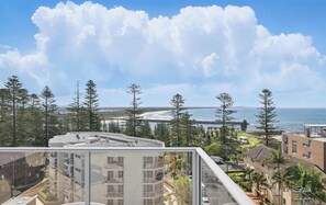 Un immeuble de grande hauteur offrant une vue sur l’océan et les arbres.