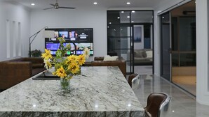 Uma cozinha moderna com uma ilha de mármore, uma TV de tela plana e um ventilador de teto.