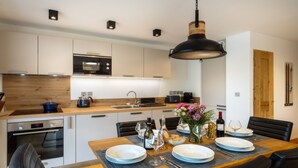 Una cocina moderna con un microondas Bosch, una encimera de madera y un comedor dispuesto con platos, vasos y un jarrón de flores.