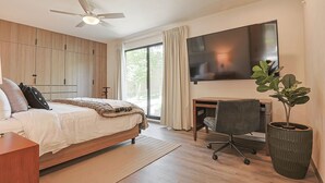 A modern hotel room with a bed, desk, chair, TV, and a large potted plant. - Modern 3BR Pool & Gym in Nueva Escondida (San Miguel de Allende)