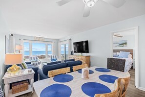 Una sala de estar con televisor, sofá y mesa de comedor con individuales.
