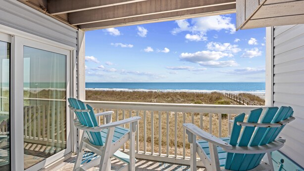 Un balcon avec deux chaises donnant sur une plage.