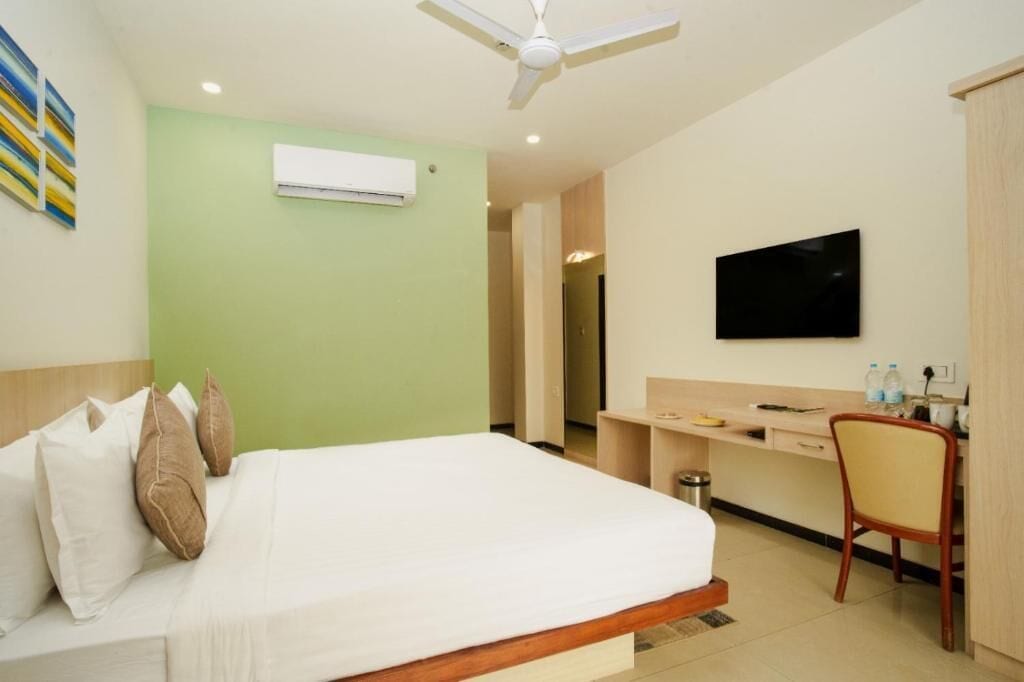 Une chambre d’hôtel équipée d’un lit, d’un bureau, d’une chaise, d’une télévision et d’un appareil de climatisation.