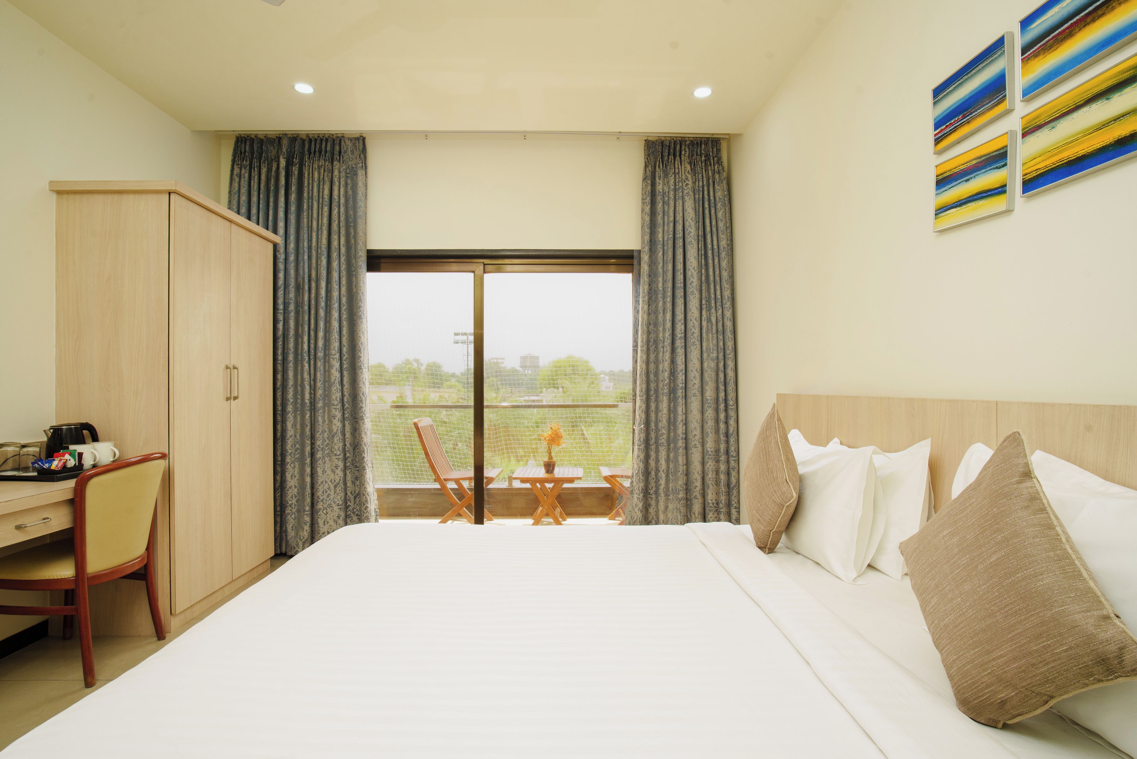 A hotel room with a bed, a desk, and a view of the outdoors.