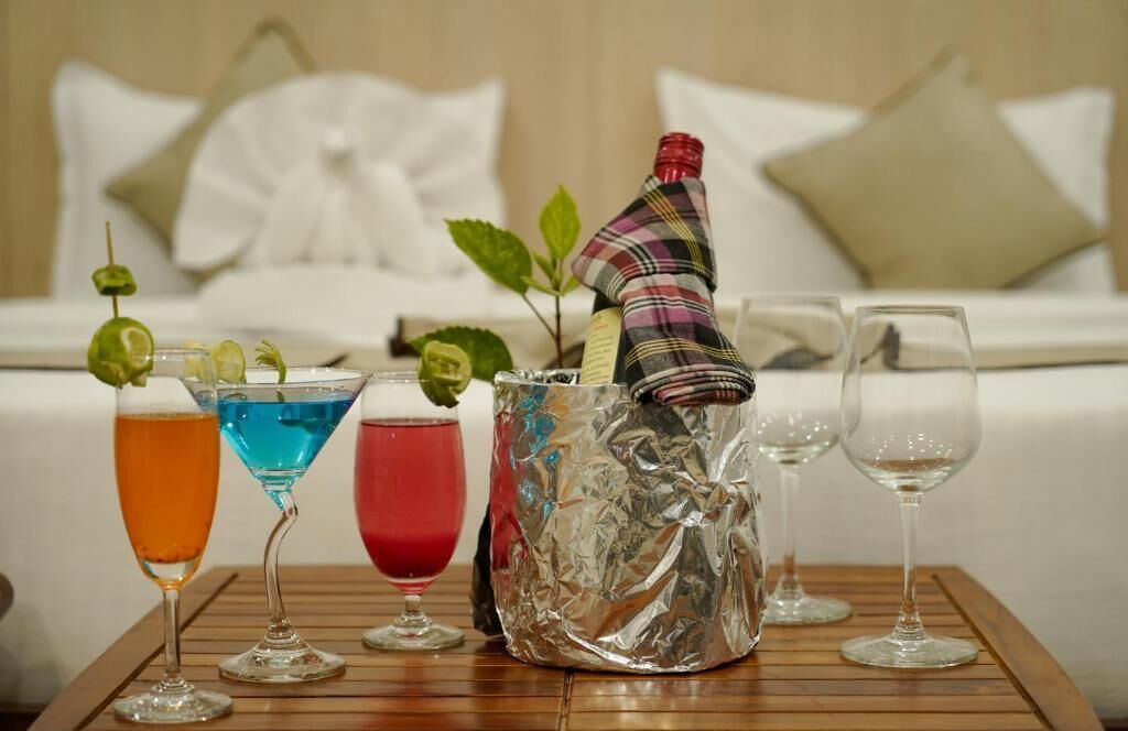 Ett bord med tre cocktails, en dekorativ glasbehållare och två tomma vinglas.
