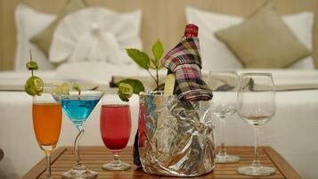 Una mesa con tres cócteles, un recipiente decorativo de vidrio y dos copas de vino vacías.