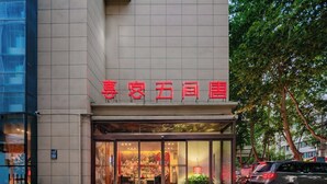 Un bâtiment doté d’une grande entrée en verre et d’une enseigne rouge au-dessus de la porte.