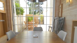 A wooden dining table with chairs, a window with a view of greenery, and a ladder leaning against the wall. - Nice little house in a good location to forget your car during the vacations. (Paris)