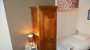 Une chambre à coucher avec deux lits simples, une armoire en bois et une lampe de chevet.