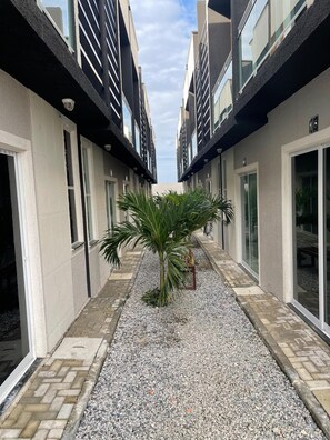 Une cour intérieure avec un palmier, un banc et un chemin bordé d’immeubles.