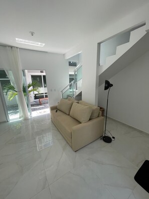 Un salon moderne avec un canapé beige, un lampadaire noir et un escalier.