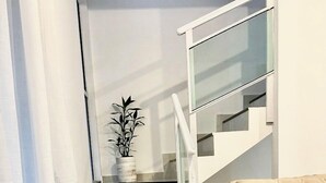 A modern interior with a staircase, a beige sofa, and a potted plant. - House in condominium on the avenue on the beach of Cumbuco close everything 5🏄 (Caucaia)