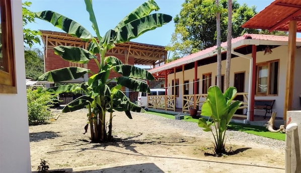 Un edificio con techo rojo y un espacio al aire libre cubierto, con suelo de tierra.